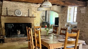 A rustic dining area with a stone fireplace, wooden chairs, and a large table. - House near the canal (Meilhan-sur-Garonne)
