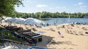 Ein Strand mit Zelten, Liegestühlen und einer Anlegestelle am See.