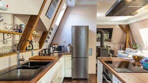 Eine kompakte Küche mit Edelstahlkühlschrank, Holz Arbeitsplatten und einem eingebauten Backofen.