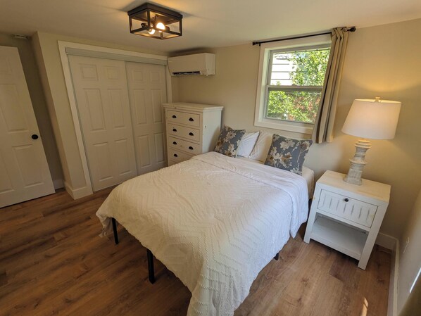 Un dormitorio con cama, mesita de noche, cómoda y una ventana con cortinas.