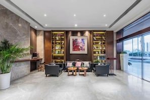 A modern lobby with a seating area, bookshelves, and a large window with a city view. - Yitel Hotel(Guangzhou Pazhou Exhibition Center Canton Tower) (Guangzhou)