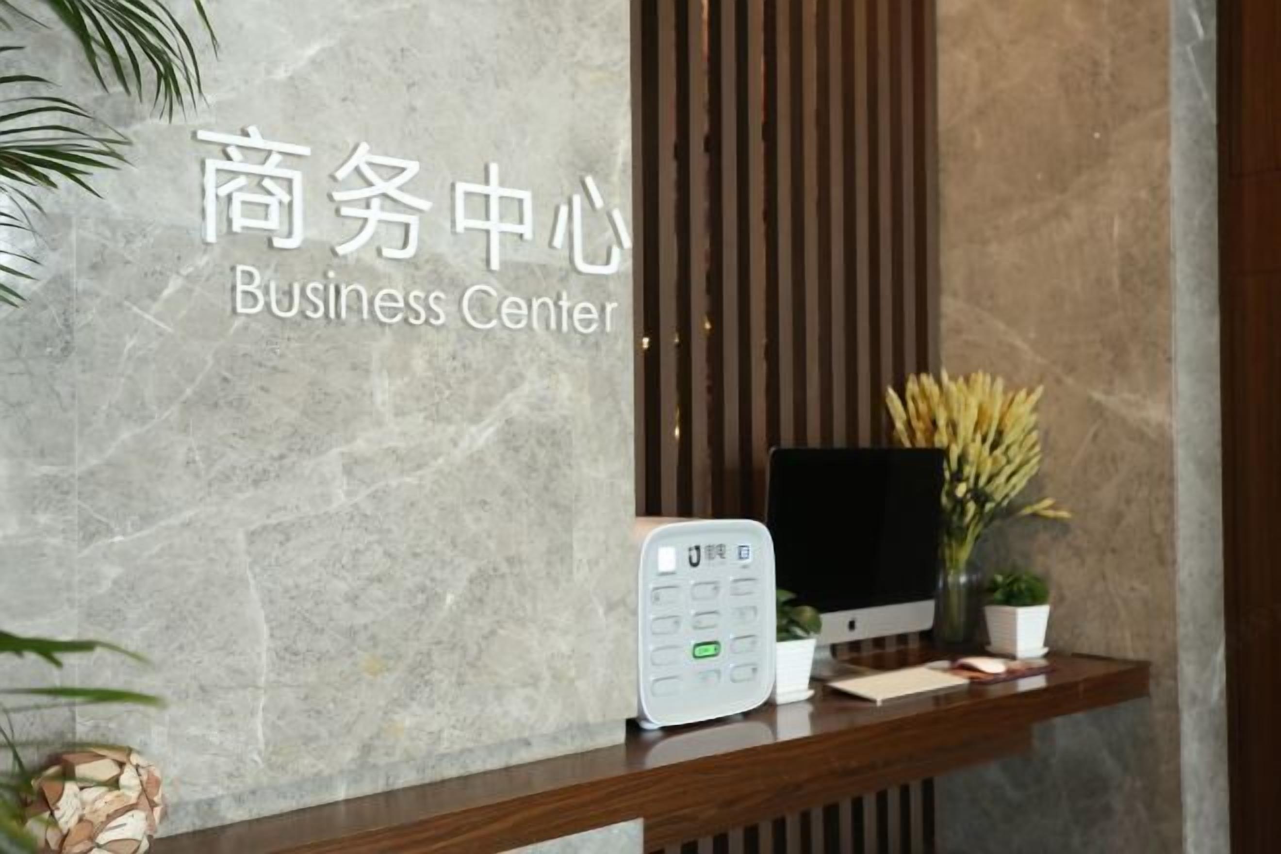 A reception desk with a digital keypad, a computer monitor, and a potted plant.