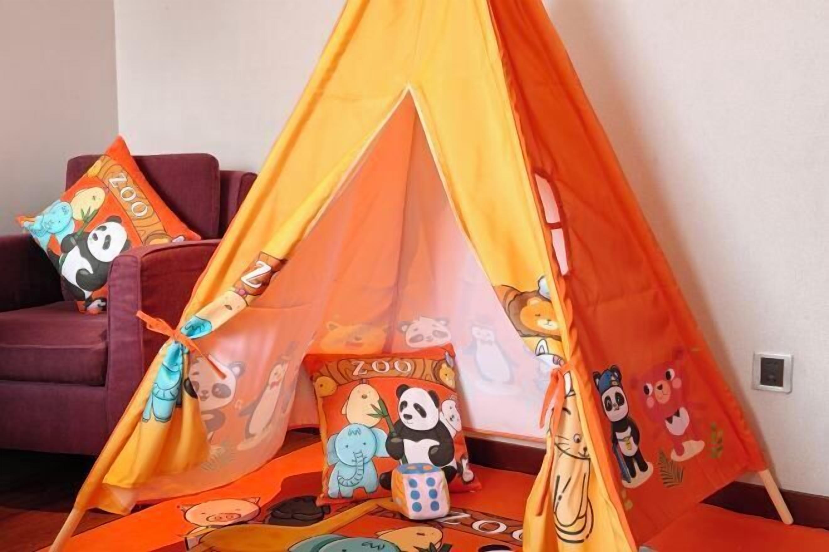 A room with a tent-like structure, pillows with panda prints, and a sofa.