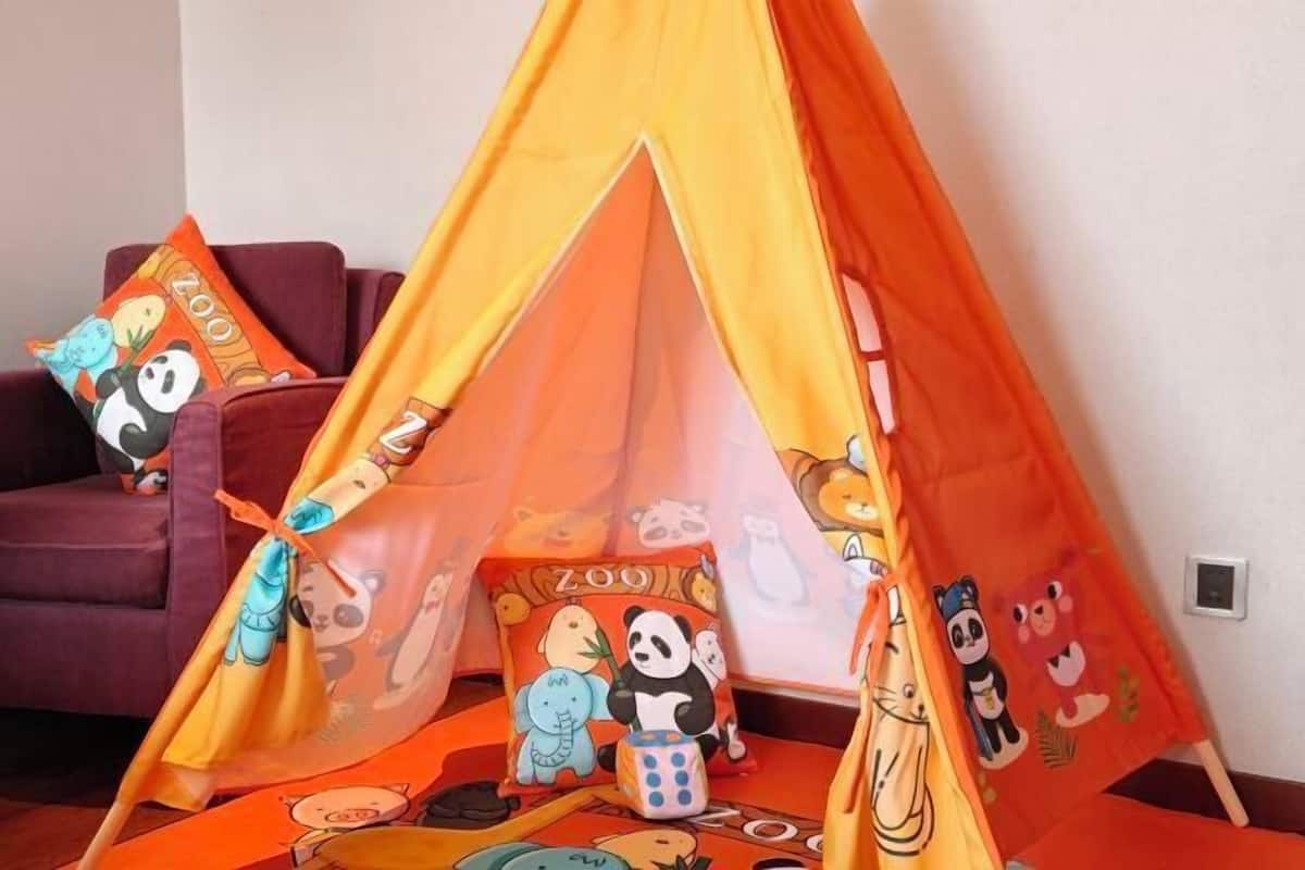 A room with a tent-like structure, pillows with panda prints, and a sofa.
