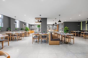 A spacious dining area with multiple tables and chairs, a central seating area, and pendant lighting. - Yitel Hotel(Guangzhou Pazhou Exhibition Center Canton Tower) (Guangzhou)