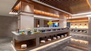 Een moderne hotellobby met meerdere niveaus, een centraal receptiegedeelte, diverse zithoeken en een gepolijste vloer.