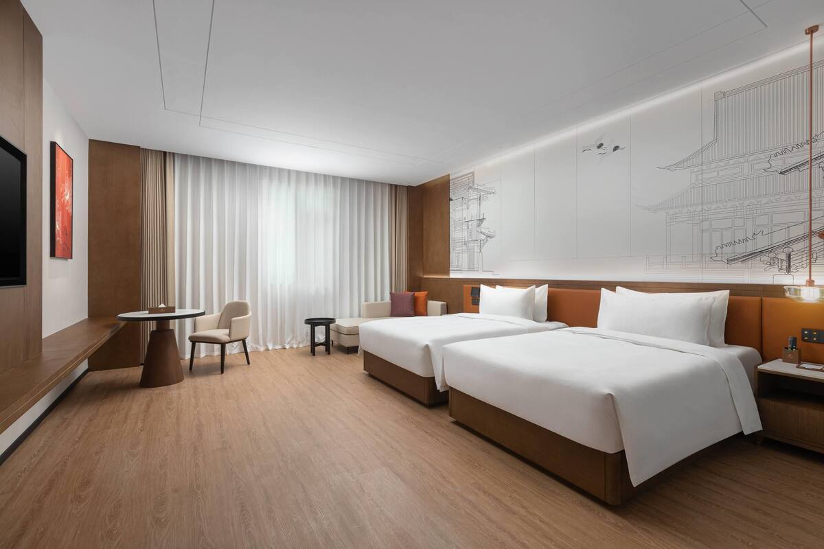 Une chambre d’hôtel avec deux lits, une télévision, un bureau et une chaise.