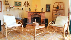 A cozy living room with a fireplace, two wicker chairs, a patterned floor, and various decorative items. - La Corte No.3 (Massa Lubrense)