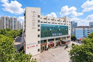 A multi-story building with a large glass facade, signage indicating a business center, and a parking area in front. - Hangzhou Sanli Jingchen Hotel (Hangzhou)