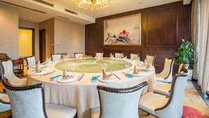 Une salle de conférence équipée d’une table ronde, de chaises et d’un lustre.