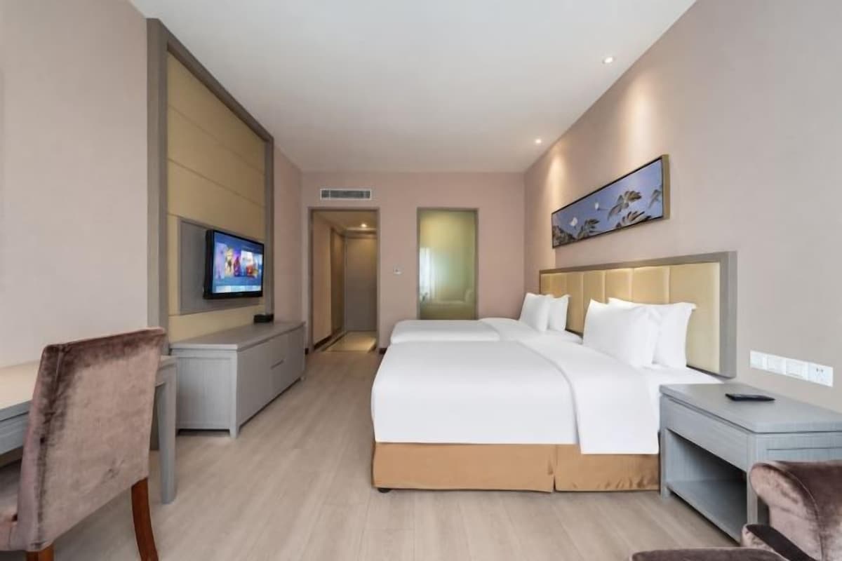 Une chambre d’hôtel avec un grand lit, un bureau, une chaise, une télévision et un tableau au mur.