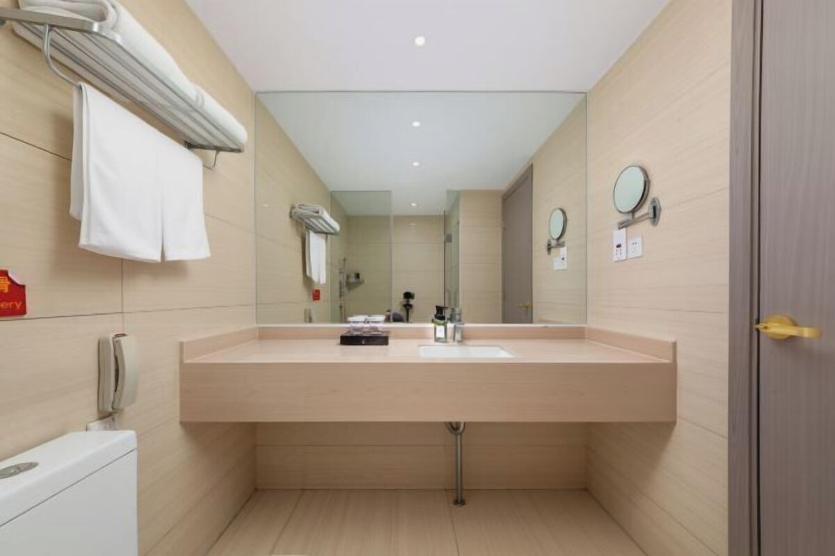 Ein modernes Badezimmer mit einem großen Waschbecken, Spiegeln, einem Handtuchhalter und einer Toilette.