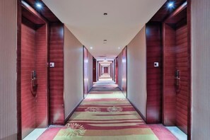 A hotel corridor with wooden doors, a carpeted floor, and a ceiling light fixture. - Hangzhou Tong Huan Hotel (Hangzhou)