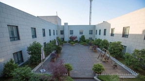 Un patio con piso de madera, rodeado de edificios blancos con numerosas ventanas.