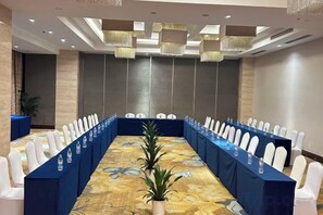 A conference room with a long table, white chairs, and a blue tablecloth. - Hangzhou Tong Huan Hotel (Hangzhou)