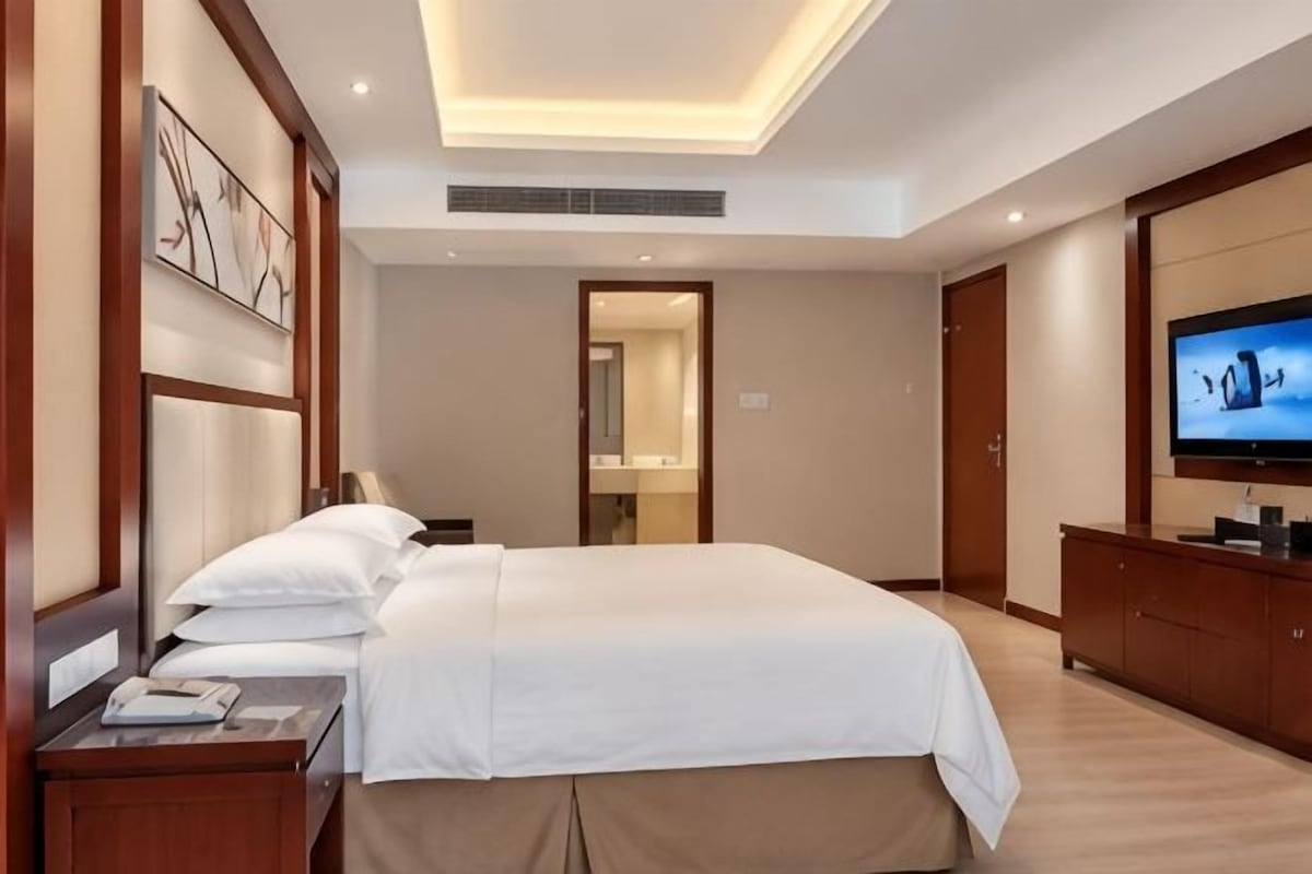 Une chambre d’hôtel avec un grand lit, une télévision, un bureau et une armoire.