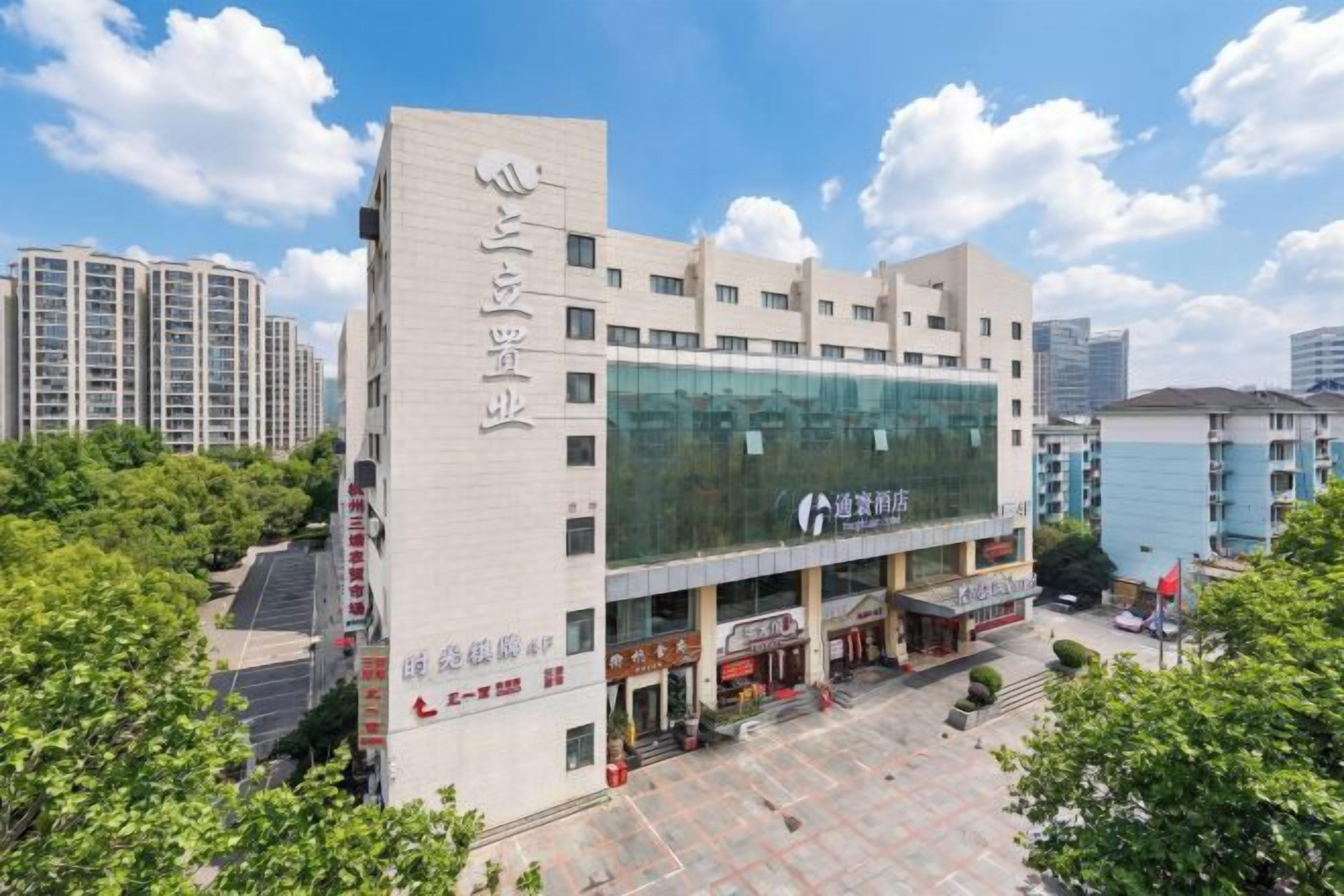 Un edificio de varios pisos con un letrero llamativo en la fachada, un amplio ventanal en el segundo piso y un patio empedrado al frente.