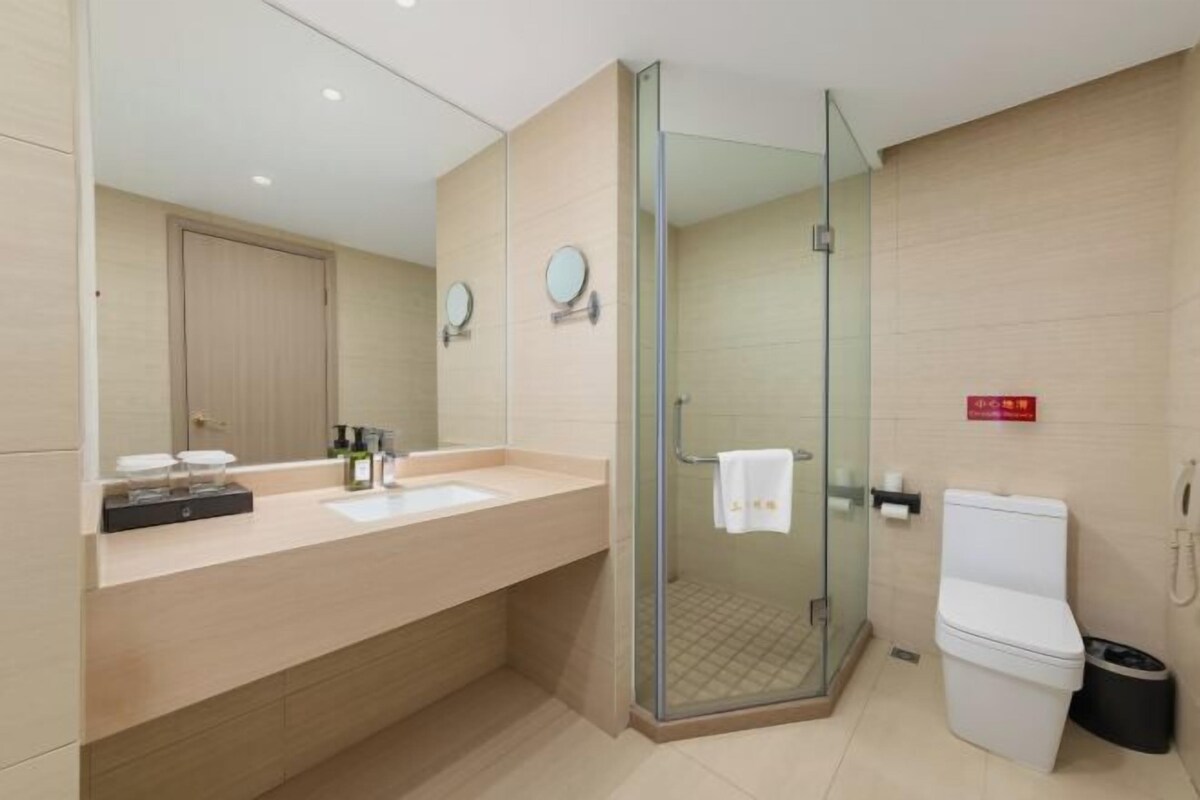Ein modernes Badezimmer mit Duschkabine aus Glas, Toilette und Waschbecken mit Spiegel.
