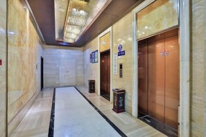 A hotel corridor with marble walls, an elevator, and a reception desk. - Hangzhou Sanli Jingchen Hotel (Hangzhou)
