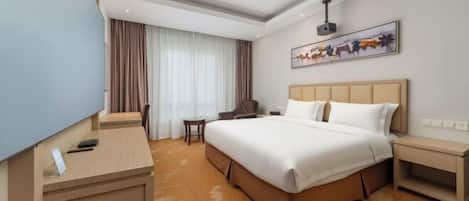 A hotel room with a large bed, a desk, a chair, a small table, and a TV.