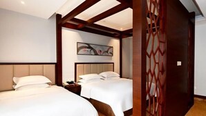 Une chambre d’hôtel avec deux lits, une tête de lit, une table de chevet, un panneau décoratif mural et une cloison en bois.