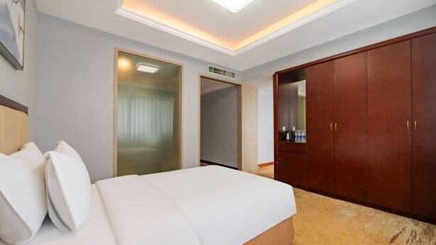 Une chambre d’hôtel avec un lit, une armoire et un miroir.