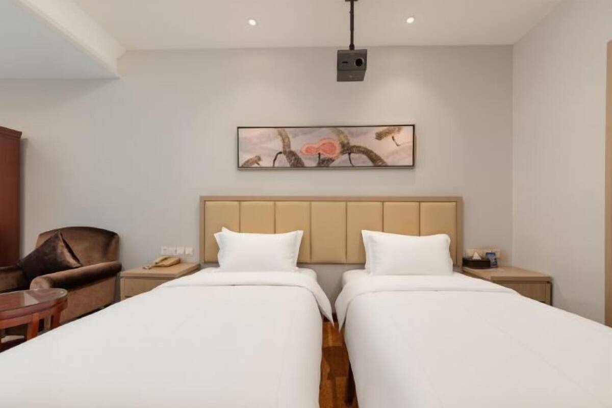 Een hotelkamer met twee bedden, een hoofdeinde, een nachtkastje, een stoel en een tafel.
