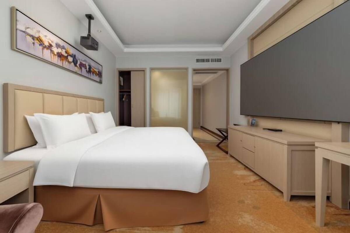 Een hotelkamer met een bed, een bureau, een televisie en een kledingkast.