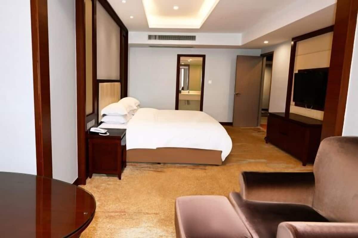 Een hotelkamer met een bed, nachtkastje, televisie en zithoek.