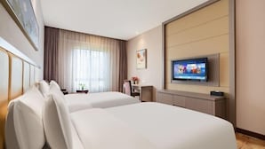 Une chambre d’hôtel avec deux lits, une télévision, un bureau et une fenêtre avec des rideaux.