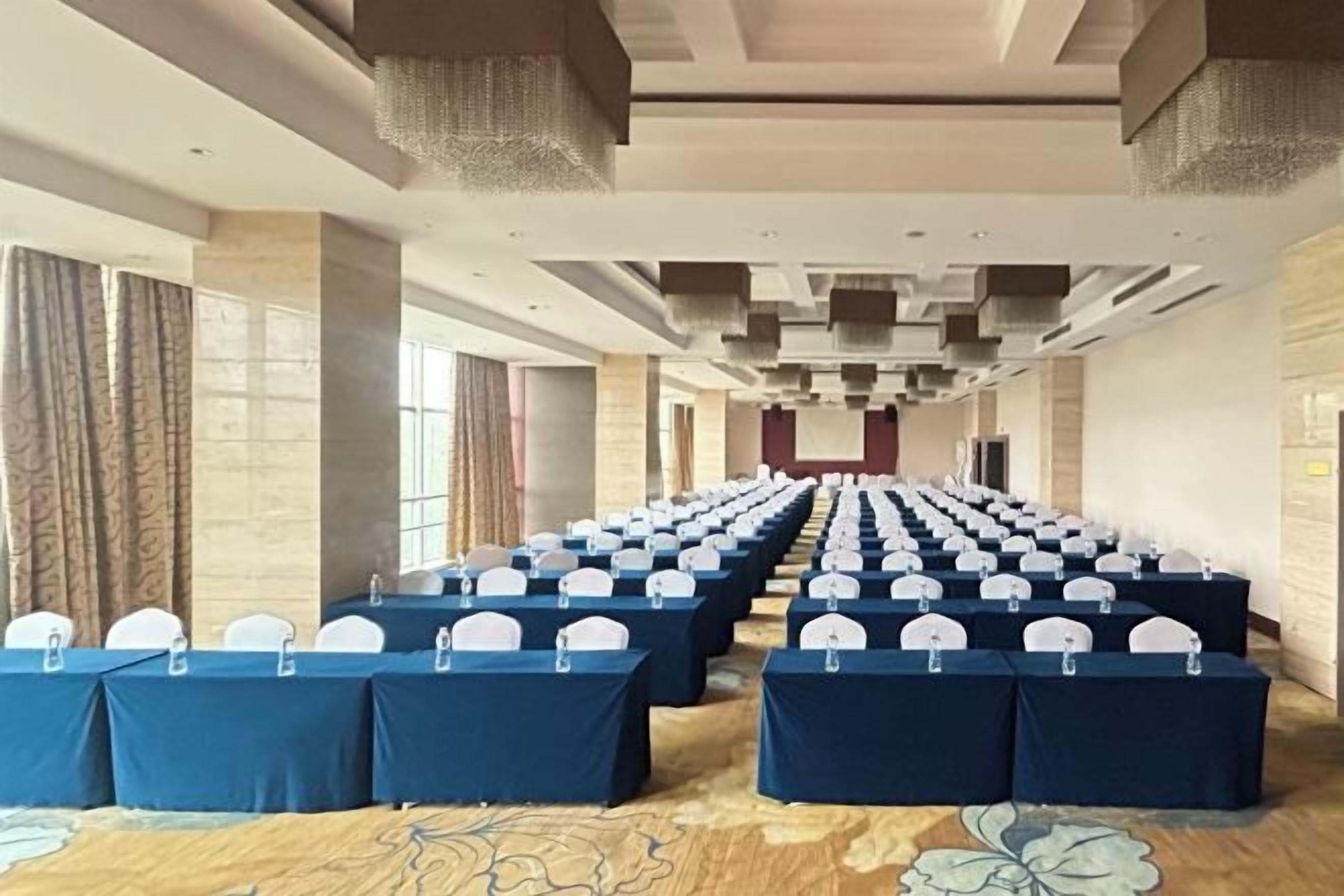 A conference room with rows of tables, chairs, and microphones, indicating a space for meetings or events.