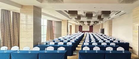 A conference room with rows of tables, chairs, and microphones, indicating a space for meetings or events.