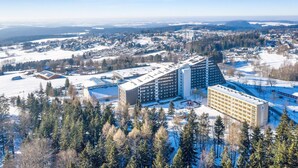 A large hotel complex with multiple buildings, surrounded by snow-covered fields and trees. - Appartment im Ferienpark in Schoneck (Schoeneck)