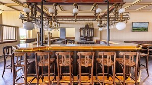 A bar area with wooden chairs, a bar counter, and a chandelier. - Appartment im Ferienpark in Schoneck (Schoeneck)
