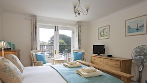 Ein Schlafzimmer mit einem Bett, einem Schreibtisch, einem Stuhl, einem Fernseher und einem Ventilator.