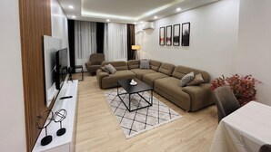Una sala de estar moderna con un sofá modular, un televisor y una mesita.