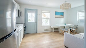 Une cuisine moderne dotée d’un réfrigérateur encastré, d’un coin repas avec une table et des chaises, et d’une porte bleu clair.