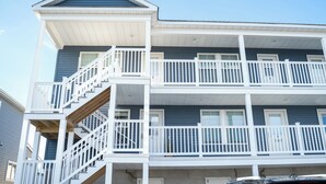 Un immeuble résidentiel à plusieurs étages, doté de balustrades blanches et d’un escalier central.