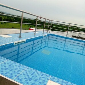 A swimming pool with a tiled edge and metal railings, surrounded by a grassy area and trees. - Cozy studio in enjoyable Mtwapa with WiFi, (Mtwapa)