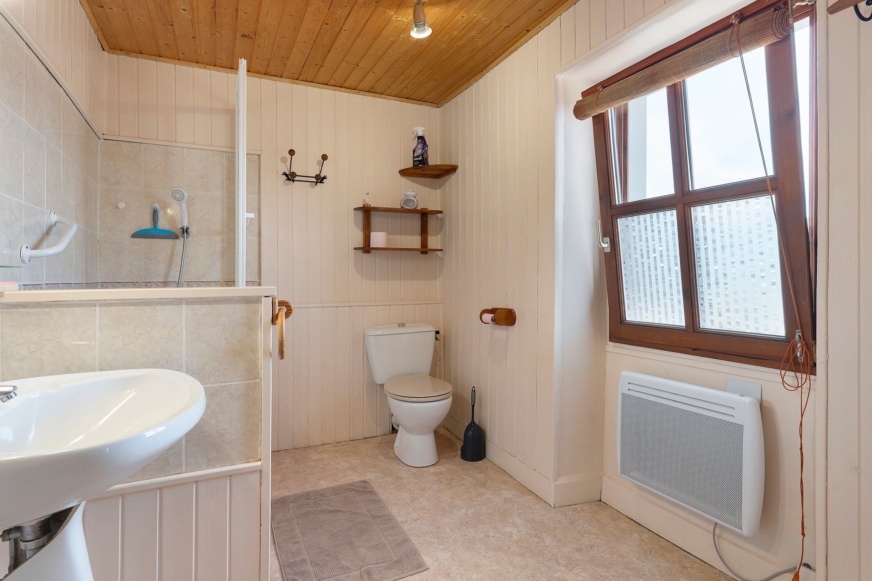 Une salle de bain équipée de toilettes, d’une douche, d’un lavabo et d’un radiateur.