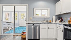A kitchen with white cabinets, a dishwasher, a sink, and a window above the countertop. - New! Lakeview at Branch Lake (Ellsworth)