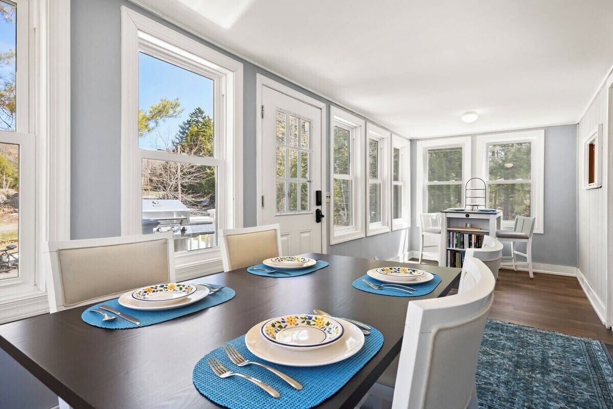 A dining area with a long table, chairs, and a view of the outdoors.