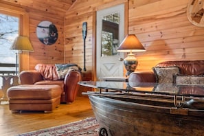Interior acogedor de una cabaña con detalles de madera, un bote en primer plano y una puerta con ventana.