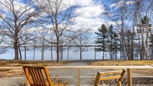 Two wooden chairs on a wooden deck with a view of a lake and trees. - Cove & Cottage at Newbury Neck (Surry)