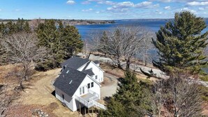 A house with a deck, surrounded by trees and a body of water. - Cove & Cottage at Newbury Neck (Surry)