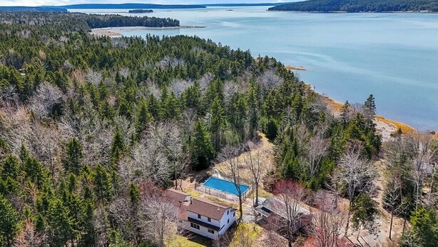 Una casa circondata da una fitta foresta e un ampio specchio d'acqua.
