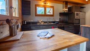 Une cuisine avec des meubles en bois, une grande fenêtre et des appareils électroménagers modernes.