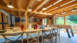 Un intérieur en bois avec une table à manger dressée pour quatre personnes, entourée de chaises en bois.