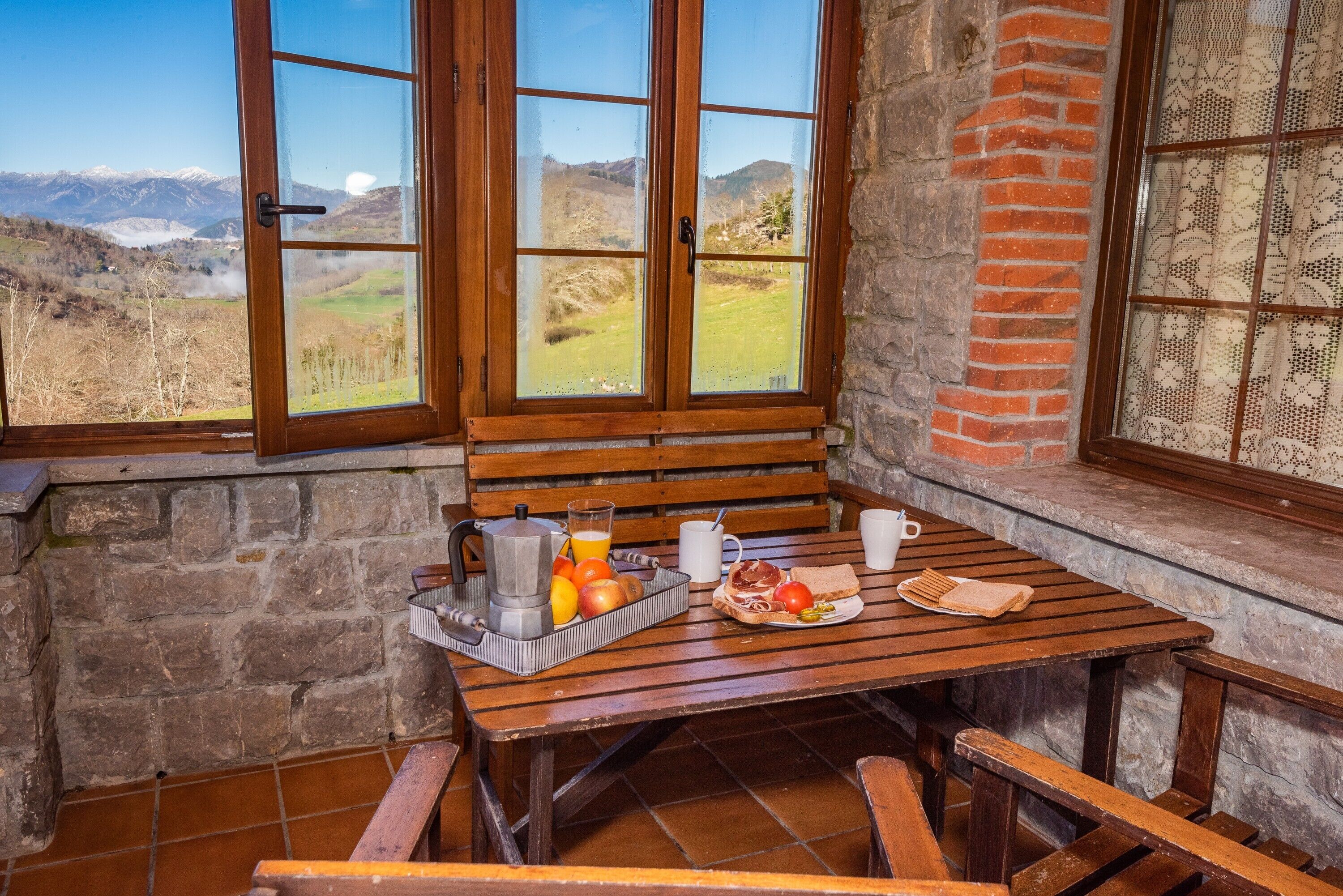 Una mesa de madera con alimentos para el desayuno y vistas a montañas.