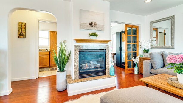 A living room with a fireplace, a sofa, a coffee table, and a dining table. - Steps to Ocean: Manhattan Beach Gem w/ Deck! (Manhattan Beach)